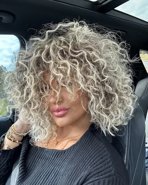 Voluminous Platinum Blonde Curls with Full Fringe